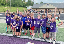 Kids on football field wearing purple cheering