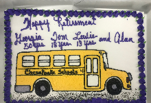 cake with white, purple icing with a yellow school bus that reads congratulations