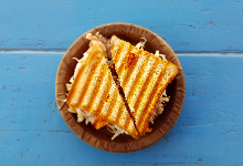 blue background with sandwich sitting on wood plate