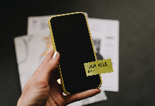 Green cell phone with hand and a yellow sign here sticker