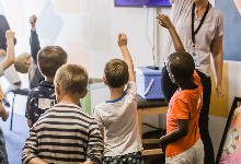 School kids raising hands in classroom 