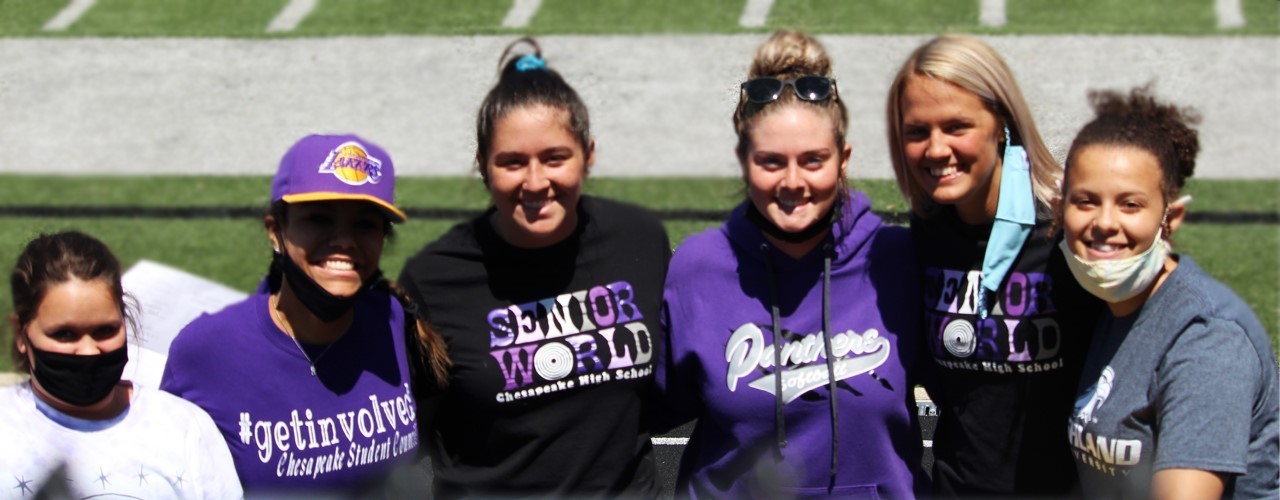 6 girls standing on football field wearing purple chesapeake shirts