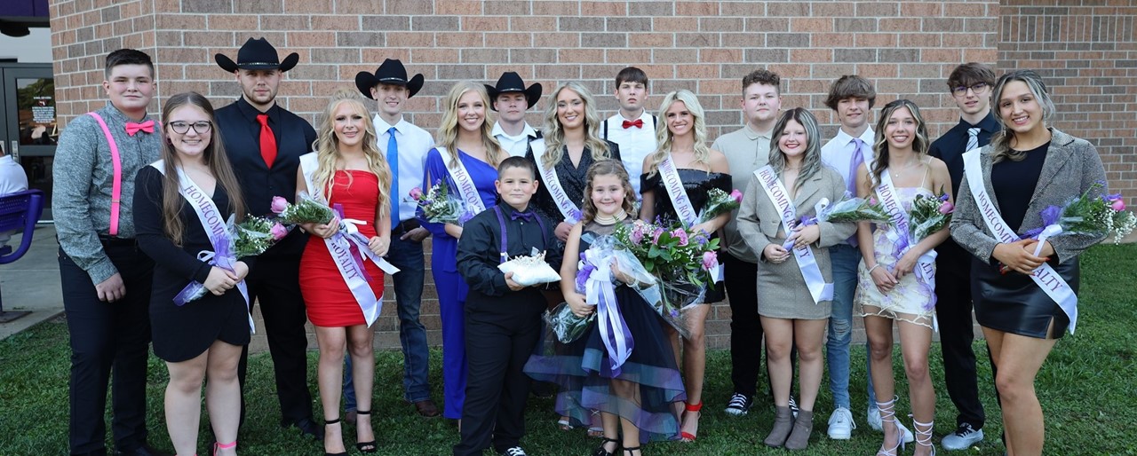 Group of students in formal wear smiling and holding flowers