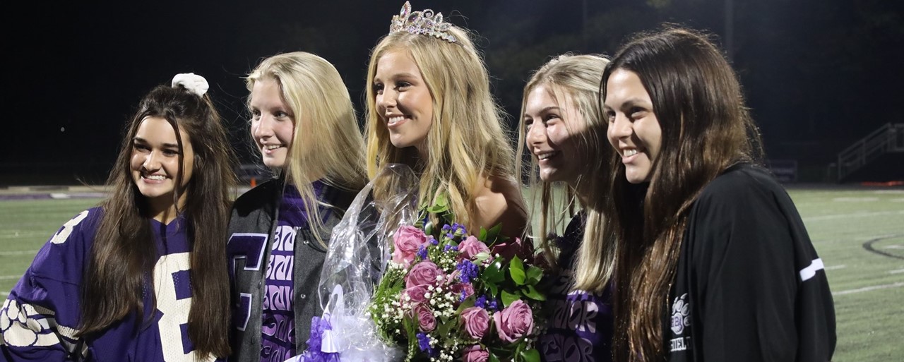 group of girls on football field with flowers 