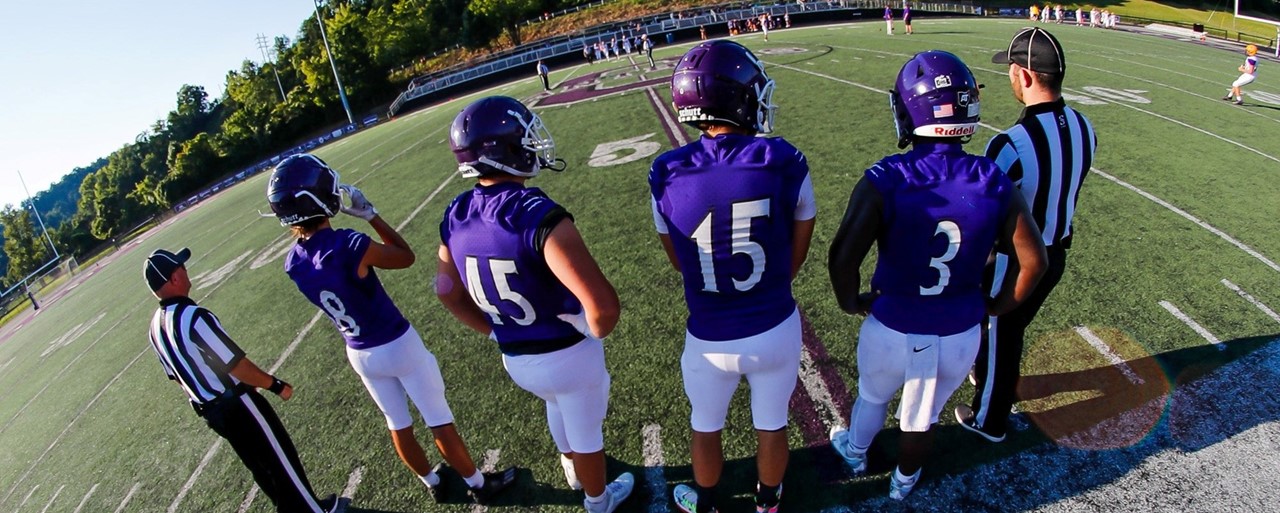 Football players and two refs standing on field