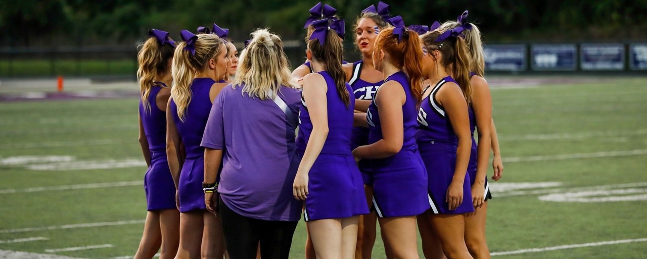 Cheerleaders standing on field wearing purple